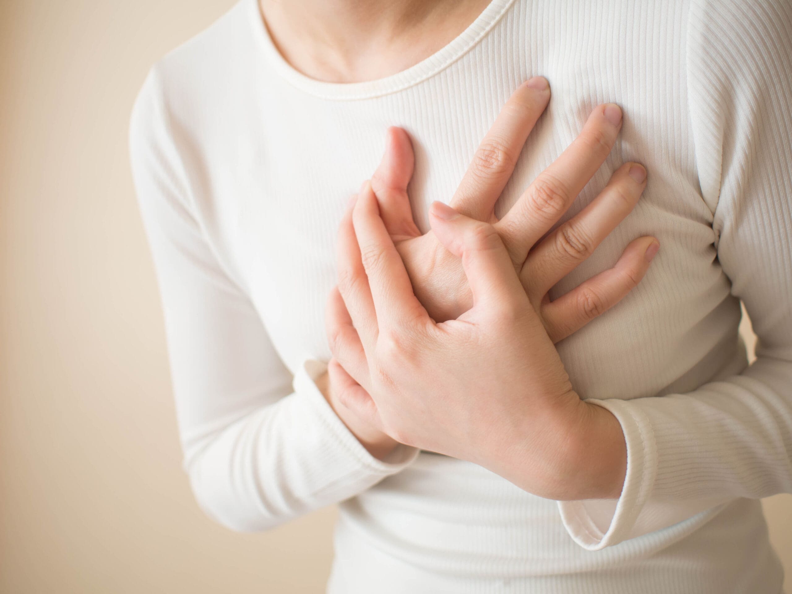 Heart attack/problems. Young female suffering from severe chest pain. Warning signs of unstable angina or myocardrial infarction disease. Health care and cardiological concept. Close up. Copy space. Breast and chest pain