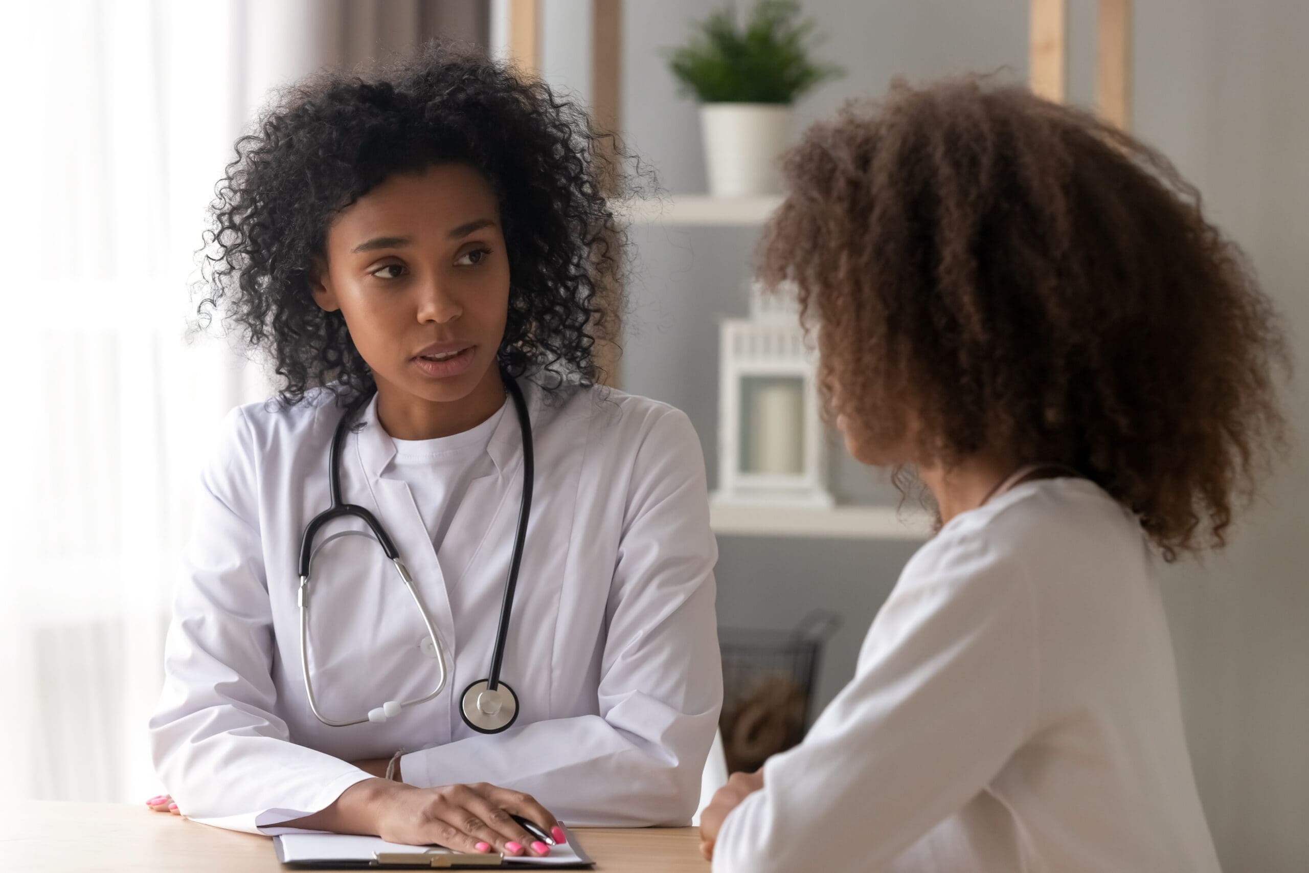 Serious black female doctor consult teenage girl Medical Procedure Laparoscopy