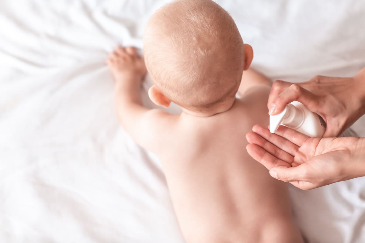 Mother are applying a lotion cream on the baby body after bath. changing the baby nappy in nursery. massage for baby. concept cleaning wipe, pure, clean