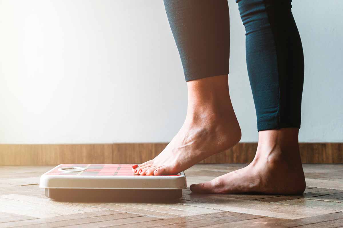 Female checking kilogrammes getting on the scale – self care and