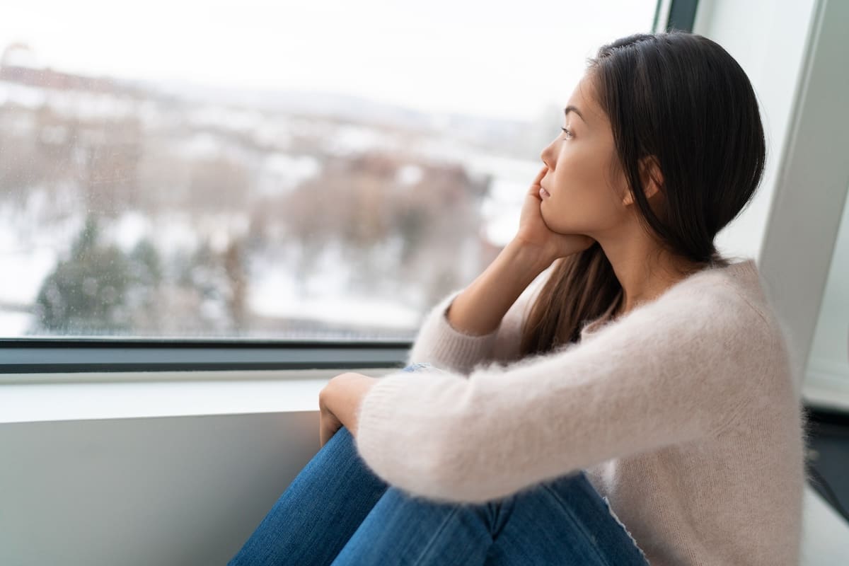 Winter seasonal affective disored SAD depression mood alone Asian girl feeling lonely – stress, anxiety, melancholy emotions. Sadness at home. A woman lacking exposure to sunlight, and risk of vitamin D deficiency